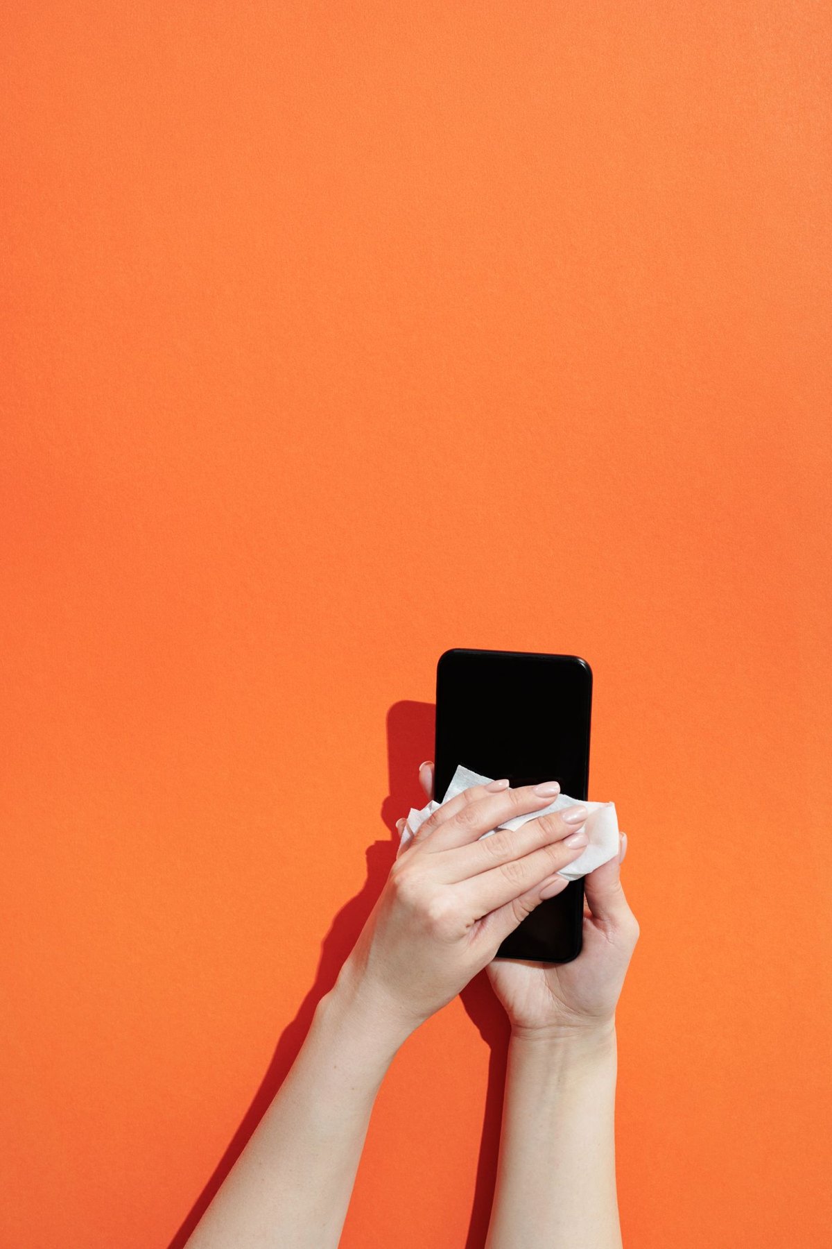 Person wiping a phone screen with a cloth