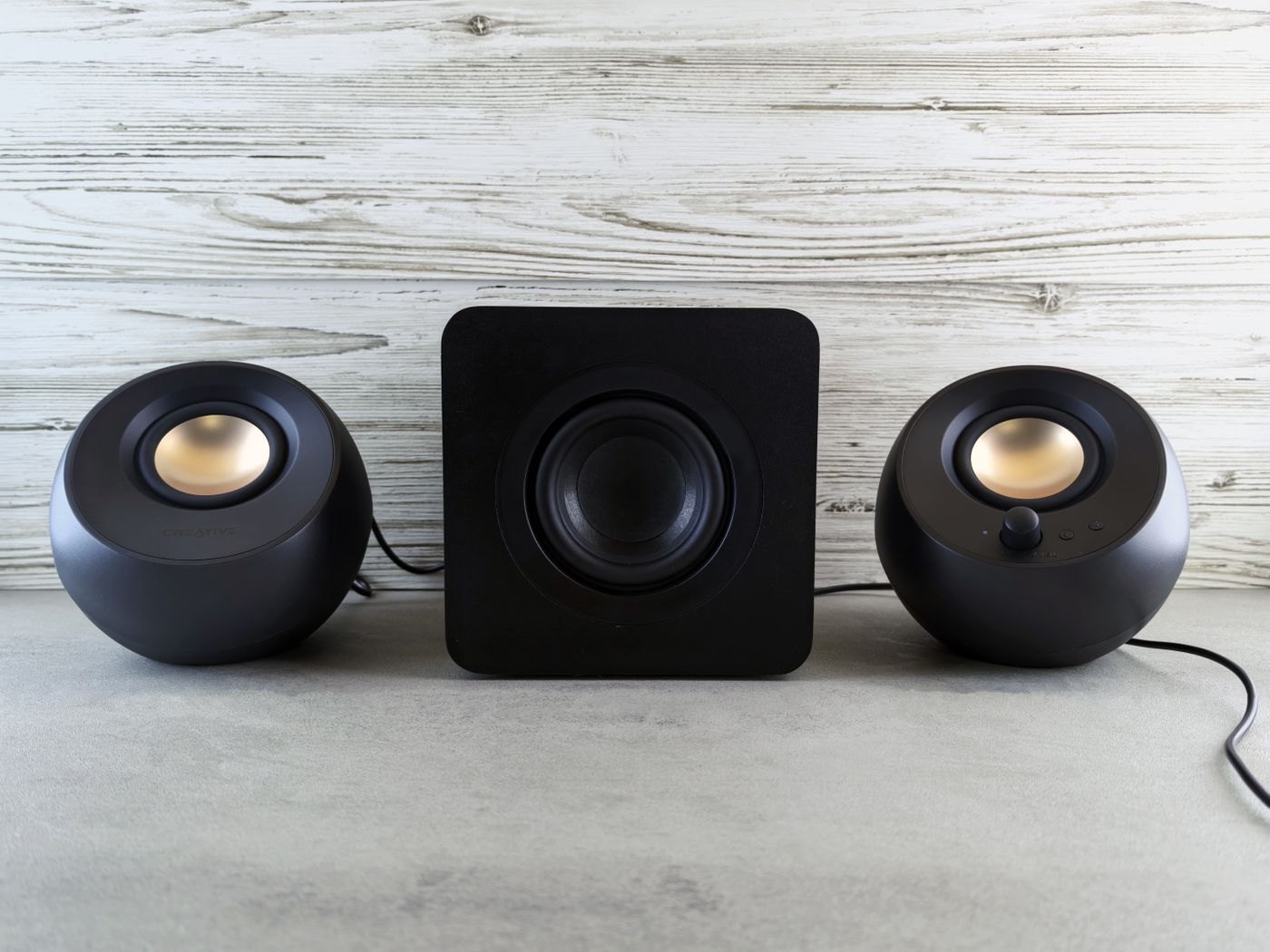 Two compact speakers and a subwoofer on a light surface