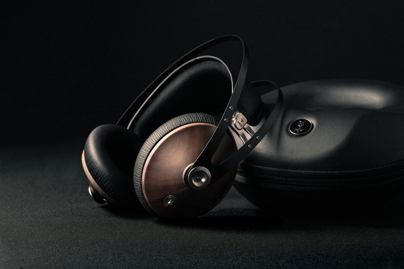 Black headphones beside their protective carrying case