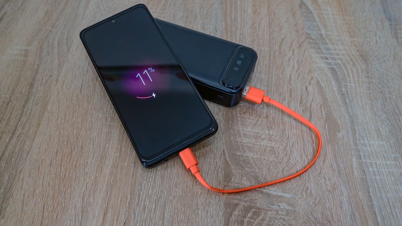 Phone connected to a portable battery by an orange cable