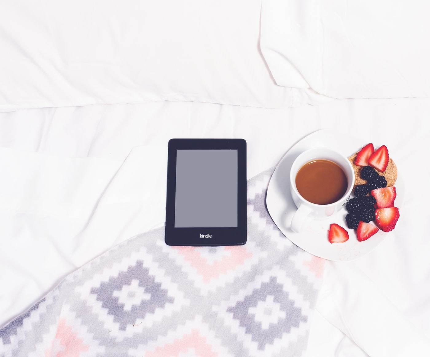 E-reader and a cup on a light blanket