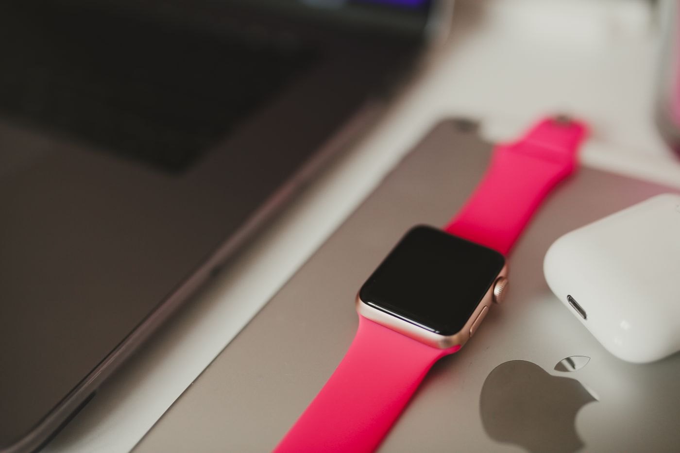 Smartwatch with a bright band resting beside a laptop