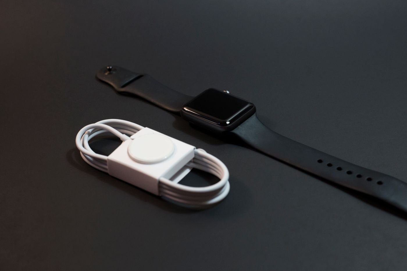 Smartwatch beside its coiled magnetic charging cable
